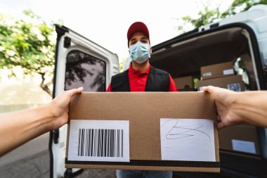 Corona virüsünün yayılmasını önlemek için yüz koruyucu maske takan teslimatçı Coronavirus salgını sırasında çalışan genç ekspres kurye teslimat ve çevrimiçi satın alma kavramı