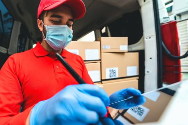 Corona virüsünün yayılmasını önlemek için yüz koruyucu maske takan teslimatçı Coronavirus salgını sırasında çalışan genç ekspres kurye teslimat ve çevrimiçi satın alma kavramı