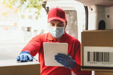 Corona virüsünün yayılmasını önlemek için yüz koruyucu maske takan teslimatçı Coronavirus salgını sırasında çalışan genç ekspres kurye teslimat ve çevrimiçi satın alma kavramı