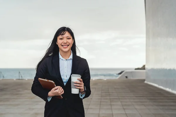 Asian business woman holding smart tablet and drinking take away coffee outside office - Entrepreneurship professional job concept