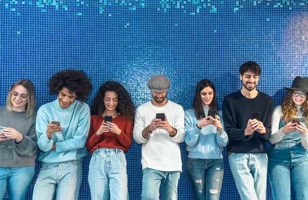 Jongeren Die Mobiele Smartphone Gebruiken Terwijl Tegen Een Blauwe Achtergrond — Stockfoto