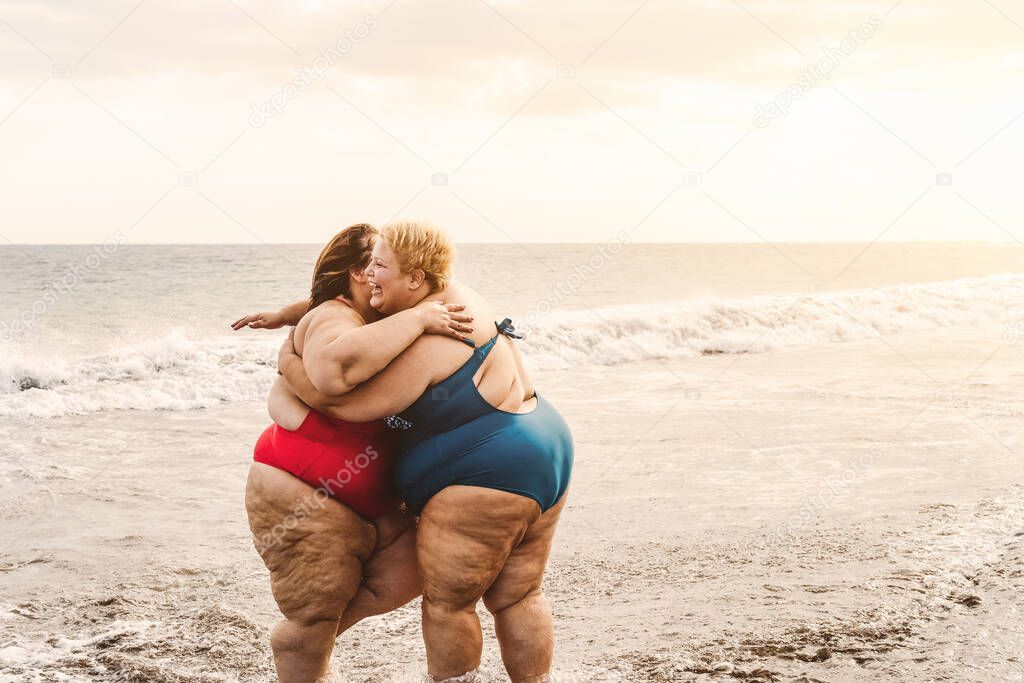 Happy plus size women having fun on sunny day at beach during vacation time
