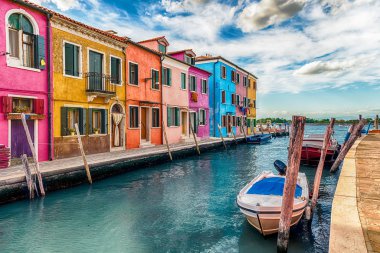 İtalya 'nın Venedik, Burano adasındaki kanal boyunca renkli boyalı evler. Ada, resimli mimarisi nedeniyle turistler için popüler bir cazibe merkezi.