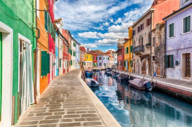 İtalya 'nın Venedik, Burano adasındaki kanal boyunca renkli boyalı evler. Ada, resimli mimarisi nedeniyle turistler için popüler bir cazibe merkezi.