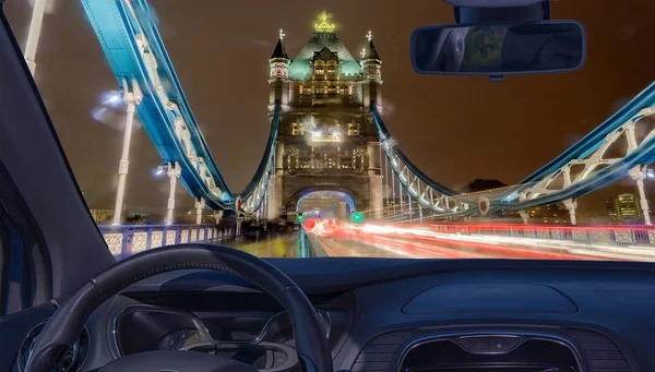 Looking through a car windshield with view of Tower Bridge at night, iconic landmark in London, UK