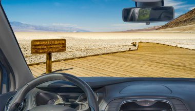 Badwater Havzası manzaralı bir arabanın ön camından ABD 'nin en düşük yükselme noktası Kaliforniya' daki Ölüm Vadisi Ulusal Parkı 'na bakıyoruz.