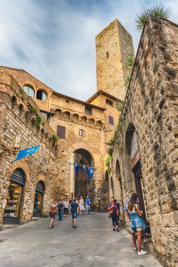 SAN GIMIGNANO, İtalya - 21 Haziran 2019 'da San Gimignano, İtalya' nın antik sokaklarını ziyaret eden turistler. Kasaba, ortaçağ mimarisi ve bir düzine kule eviyle ünlüdür.