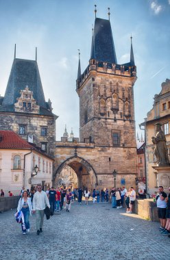 PRAG - 10 Mayıs 2024: Çek Cumhuriyeti Prag 'da güneşli bir günde Charles Köprüsü' nün altında yürüyen turistler