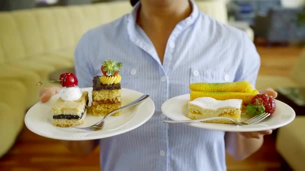 ženské číšník má v sobě dvě desky s sladké zákusky a vidličky, pěšky přes sál restaurace