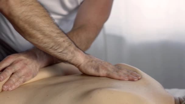 Male chiropractor is kneading muscles of back of female patient, curing osteochondrosis — Stock Footage Male chiropractor is kneading muscles of back of female patient, curing osteochondrosis Video Clip