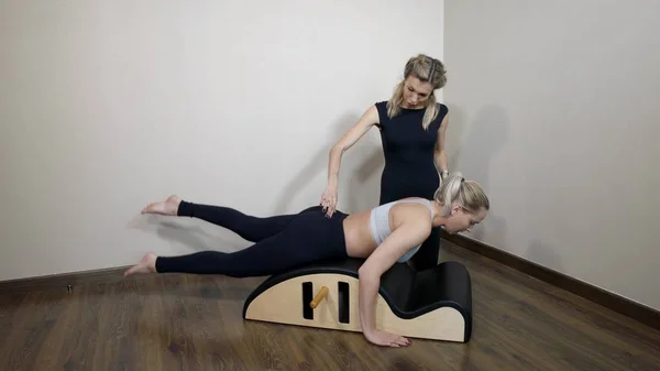 trainer is controlling and correcting position of body and spine of young sportswoman during workout