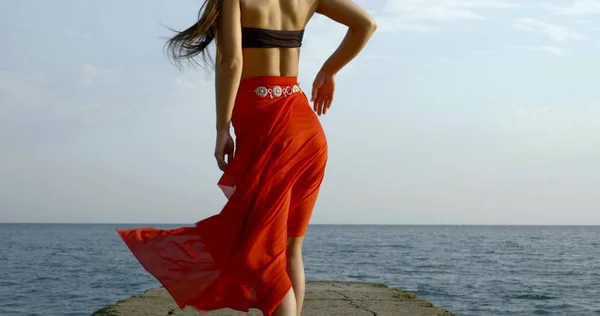 long haired girl in long open leg red skirt waved by wind