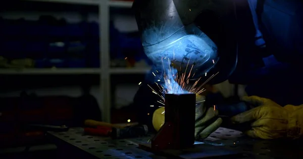 welder in mask works with metal parts in sparks slow motion