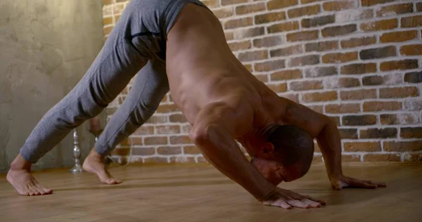 yoga instructor does down dog against brick wall slow motion