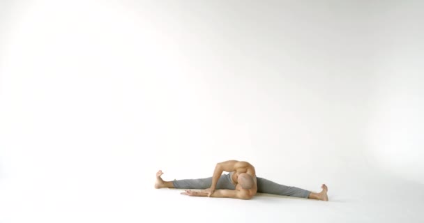 Man does yoga asana sitting and bending on mat slow motion — Stock Footage Man does yoga asana sitting and bending on mat slow motion Royalty Free Stock Footage