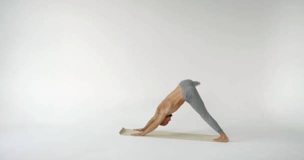 A flexible and plastic male yogi with a beard does yoga on a rug in a white Studio — Stock Footage A flexible and plastic male yogi with a beard does yoga on a rug in a white Studio Video Clip