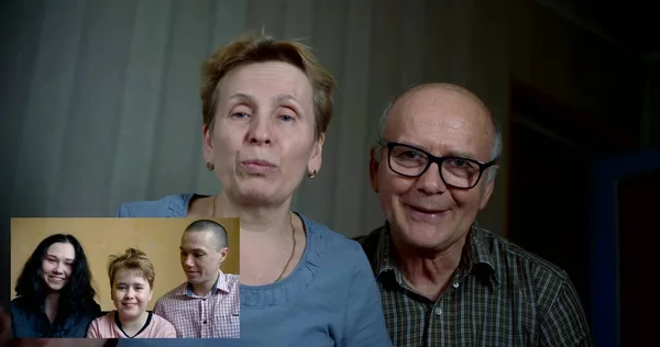 Video communication on the self-isolation of the house, an elderly couple call on the phone with young people: a girl, a guy and a little girl with short hair, communicate, smile, sit at home