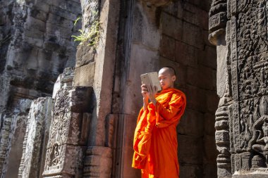 Bayon Tapınağı, Siem Reap, Kamboçya - Ekim 2018: Monk Angkor Thom Bayon tapınağında taş yüzü olan bir fotoğraf almak ve en ayırt edici özelliği sakin ve gülümseyen taş yüzü çok sayıda.