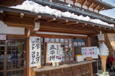Gifu, Japonya - Aralık 2018: dondurma dükkanı geleneksel ev Gassho tarzı ve bir Unesco Dünya mirası siteleri, Gifu, Japonya gibi mutlu Asya kızla kışın Shirakawa-go Köyü'nde