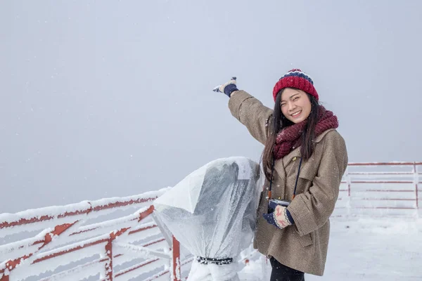 Portrait of woman with red wool hat feeling very happy and cold under snowy weather at Shin-hotaka observation deck, Japan Alps.