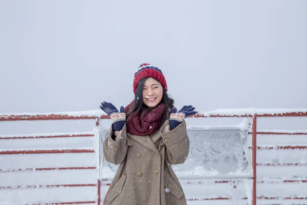 Portrait of woman with red wool hat feeling very happy and cold under snowy weather at Shin-hotaka observation deck, Japan Alps.