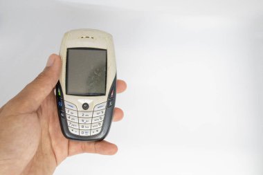 Parmak beyaz izole die kesilmiş arka plan ile cep telefonu eski nesil tutan. 1995-2010 yüzyıl boyunca geleneksel cep telefonu.