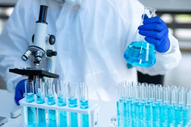 Laboratuvarda Coronavirus aşısı üzerinde çalışan bir bilim adamı. Mikroskop ile covid 19 örneğinin soyut analizi ve laboratuarda Coronavirus covid 19 kan örneği tüpü..