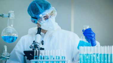 Laboratuvarda Coronavirus aşısı üzerinde çalışan bir bilim adamı. Mikroskop ile covid 19 örneğinin soyut analizi ve laboratuarda Coronavirus covid 19 kan örneği tüpü..