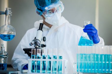 Laboratuvarda Coronavirus aşısı üzerinde çalışan bir bilim adamı. Mikroskop ile covid 19 örneğinin soyut analizi ve laboratuarda Coronavirus covid 19 kan örneği tüpü..