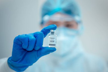Bilim adamı veya araştırmacı elinde grip, kızamık, koronavirüs, kovid-19 aşı hastalığı taşıyan mavi eldivenlerle insan klinik denemelerine aşı aşısı, ilaç ve ilaç konseptine hazırlanıyor..