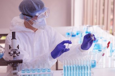 Laboratuvarda Coronavirus aşısı üzerinde çalışan bir bilim adamı. Mikroskop ile covid 19 örneğinin soyut analizi ve laboratuarda Coronavirus covid 19 kan örneği tüpü..
