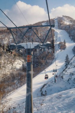 Hokkaido, Japonya - Aralık 2019 Kiroro kayak merkezinin alanı. Kayakçılar ve Snowboardcular kış boyunca Japonya 'nın Hokkaido şehrinde tamamen karla kaplı Kiroro Kayak Tatil Köyü' nde Gondola biniyorlar..