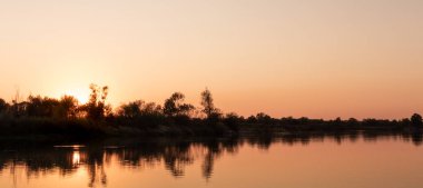 Nehirde gün batımı. Suyun üzerinde gün batımı yansıması.