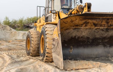 Buldozer kovası yükleniyor. Kum havuzuna yakın çekim için çekici yükleyici 