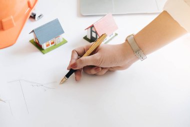 Genç kadın mimar serbest çizim, inşaat mühendisi inşaat proje ofis, inşaat kavramı küçük ev modeli ve güvenlik kask ile bir plan çizimi yakın çekim.