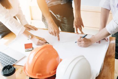 Mimar ekip beyin fırtınası planlama tasarımı, inşaat mühendisi inşaat proje ofis, inşaat kavramı küçük ev modeli ve güvenlik kask ile bir plan çizimi.