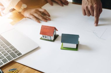 Mimar ekip beyin fırtınası planlama tasarımı, inşaat mühendisi inşaat proje ofis, inşaat kavramı küçük ev modeli ve güvenlik kask ile bir plan çizimi.