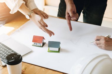 Mimar ekip beyin fırtınası planlama tasarımı, inşaat mühendisi inşaat proje ofis, inşaat kavramı küçük ev modeli ve güvenlik kask ile bir plan çizimi.