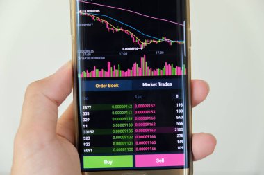 Cryptocurrency Pazar grafik ekranda fiyat sipariş listesi ve el ile smartphone odaklanmak arka plan bulanıklık. Blockchain, Fintech yatırım finansal Internet teknoloji kavramı.