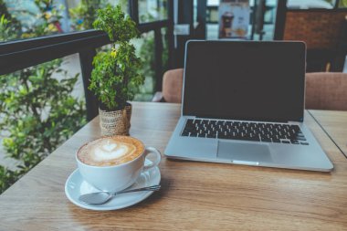 Kahve latte sanat kafe vintage renk tonu ahşap masanın üstünde laptop ile