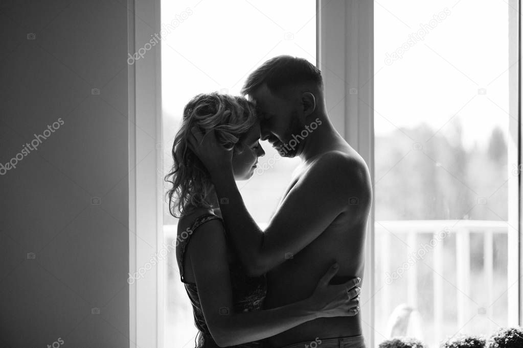 side view of two lovers against window, black and white