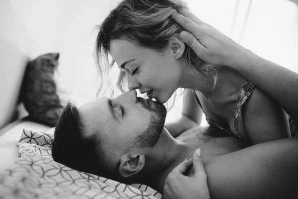 在床上亲吻年轻成人夫妇的侧面视图 — 图库照片