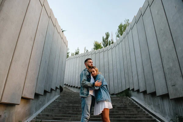 young adult couple in casual clothing on concrete steps