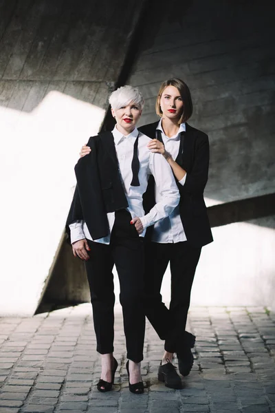 Полный Снимок Двух Женщин Классических Костюмах Позирующих Против Геометрической Бетонной — стоковое фото