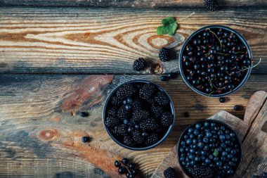 Yaban mersini, böğürtlen, ahşap arka planda kuşüzümü. Düz konum, üst görünüm, kopyalama alanı.