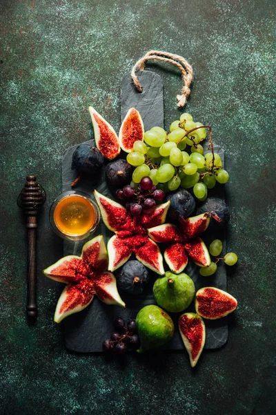 Figues fraîches et raisins au miel sur un tableau noir . — Photo