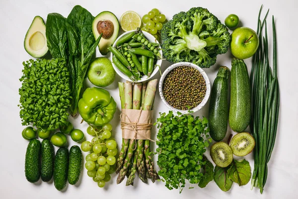 Green vegetables and fruits, greens and legumes on a white background. Healthy food and clean eating concept. Flat lay, top view.