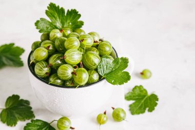 Doğal mermer zemin üzerinde beyaz seramik tabakta yaprakları olan yeşil bektaşi üzümü. Kapat, boşluğu kopyala.