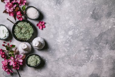 Gri arka planda doğal cilt bakım ürünleri ve pembe çiçekler. Düz konum, üst görünüm, kopyalama alanı.