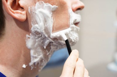 Genç adam sakalını kesiyor.